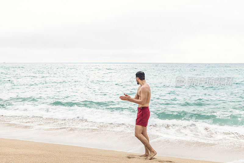 海滩上穿着红色衣服的男人。Pedn Vounder,康沃尔。